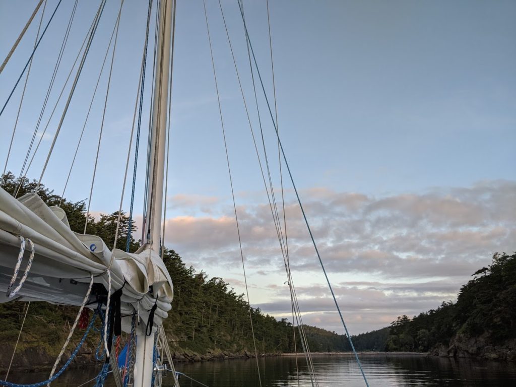 A view of the beach with the mainsail on our sailboat in the foreground at sunrise in May at Sucia Island Marine State Park in the San Juan Islands